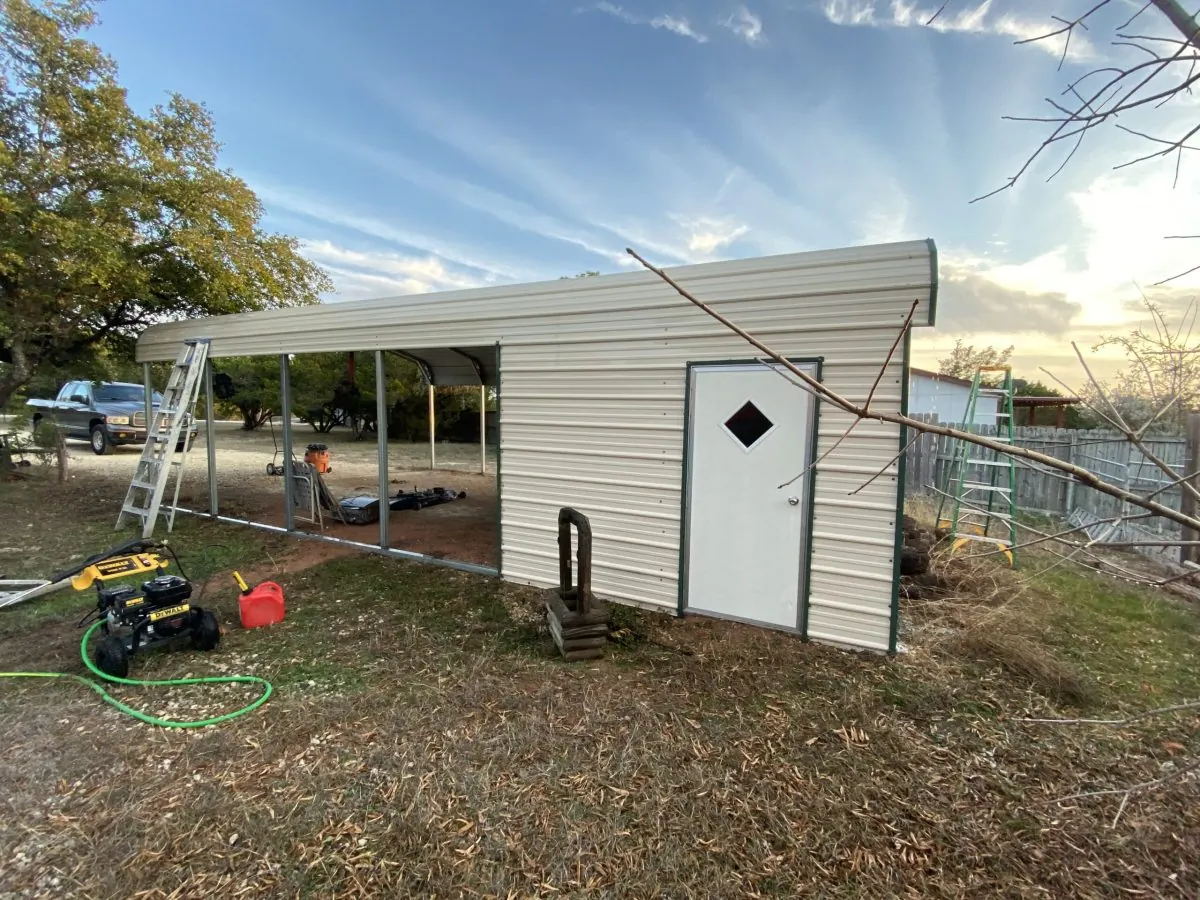 Metal carport with washing equipment and hose set up beside it