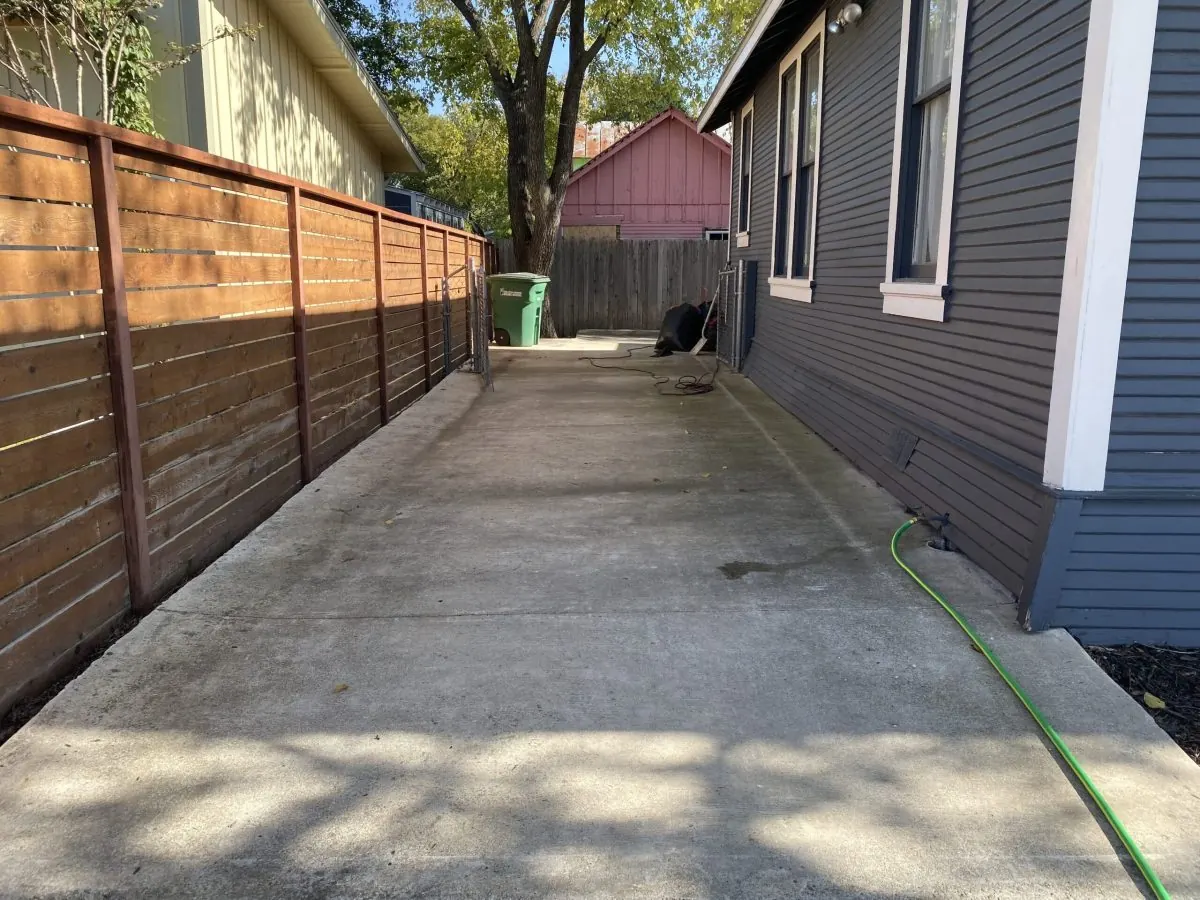Clean concrete side yard beside a wood fence and gray siding